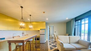 A modern kitchen with a dining area, a sofa, and a view of the outdoors. - Espana Condo Resort Pattaya Office (Pattaya)