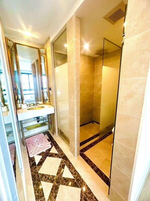A modern bathroom with a glass shower enclosure, a vanity with a sink, and a patterned floor. - Espana Condo Resort Pattaya Office (Pattaya)