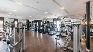 A spacious gym with various exercise machines, mirrors, and a wooden floor. - Espana Condo Resort Pattaya Office (Pattaya)