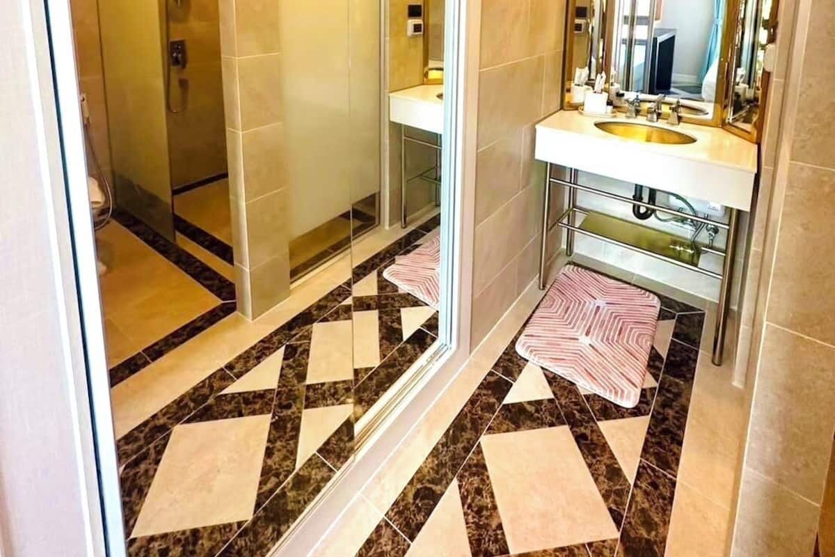 A modern bathroom with a glass shower enclosure, a vanity with a sink and mirror, and a patterned floor.