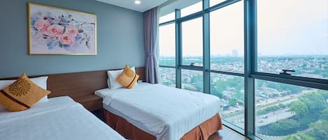 A hotel room with two beds, a large window with a city view, and a floral painting on the wall.