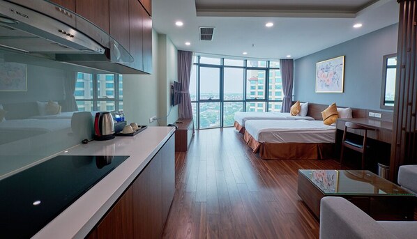 A hotel room with a kitchenette, two beds, a large window with a city view, and a dining table. - Hanoi Westlake Apartment By Netland Housing (Hanoi)