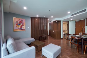 A modern living room with a sofa, ottoman, and a dining table with chairs.