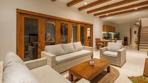 A spacious living area with a sofa, armchairs, and a coffee table. There is a sliding glass door leading to a dining area. - Peaceful Luxe Villa near Beach in Pecatu (Pecatu)