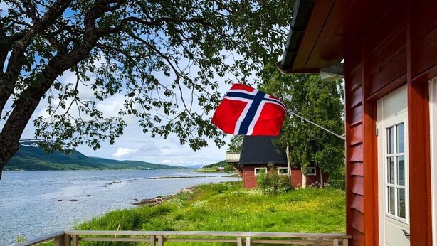 Eine Holzterrasse mit Blick auf einen See und ein Haus mit einer Flagge.