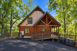 Une cabane en bois dotée d’un porche couvert et d’un petit escalier menant à l’entrée.