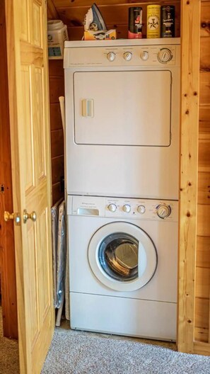 Eine kompakte, weiße, übereinander gestapelte Waschmaschine und Trockner in einem Holzschrank.