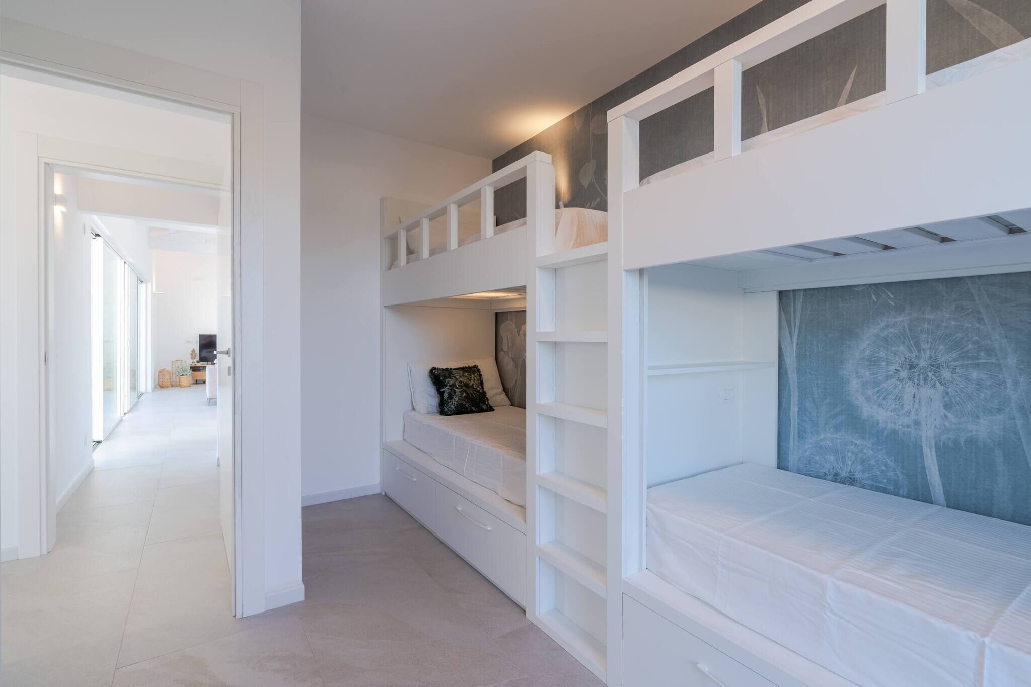 A room with bunk beds, a large window, and a dandelion artwork on the wall.