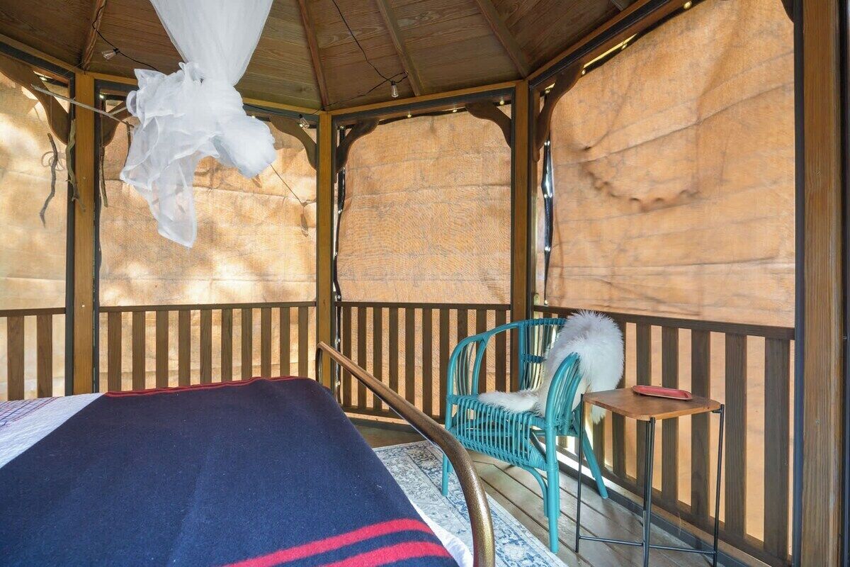 A room with a bed, a chair, a small table, and a mosquito net.