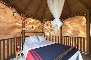 A wooden cabin-style room with a bed, a lantern, and a canopy. - Blueberry Cottage on the Ocean! (Lamoine)