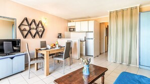 Ett kompakt bostadsutrymme med en matplats, ett litet kök och en TV.