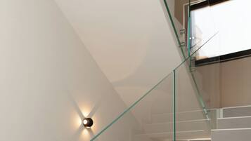 A modern staircase with glass railings and a wall-mounted light fixture.