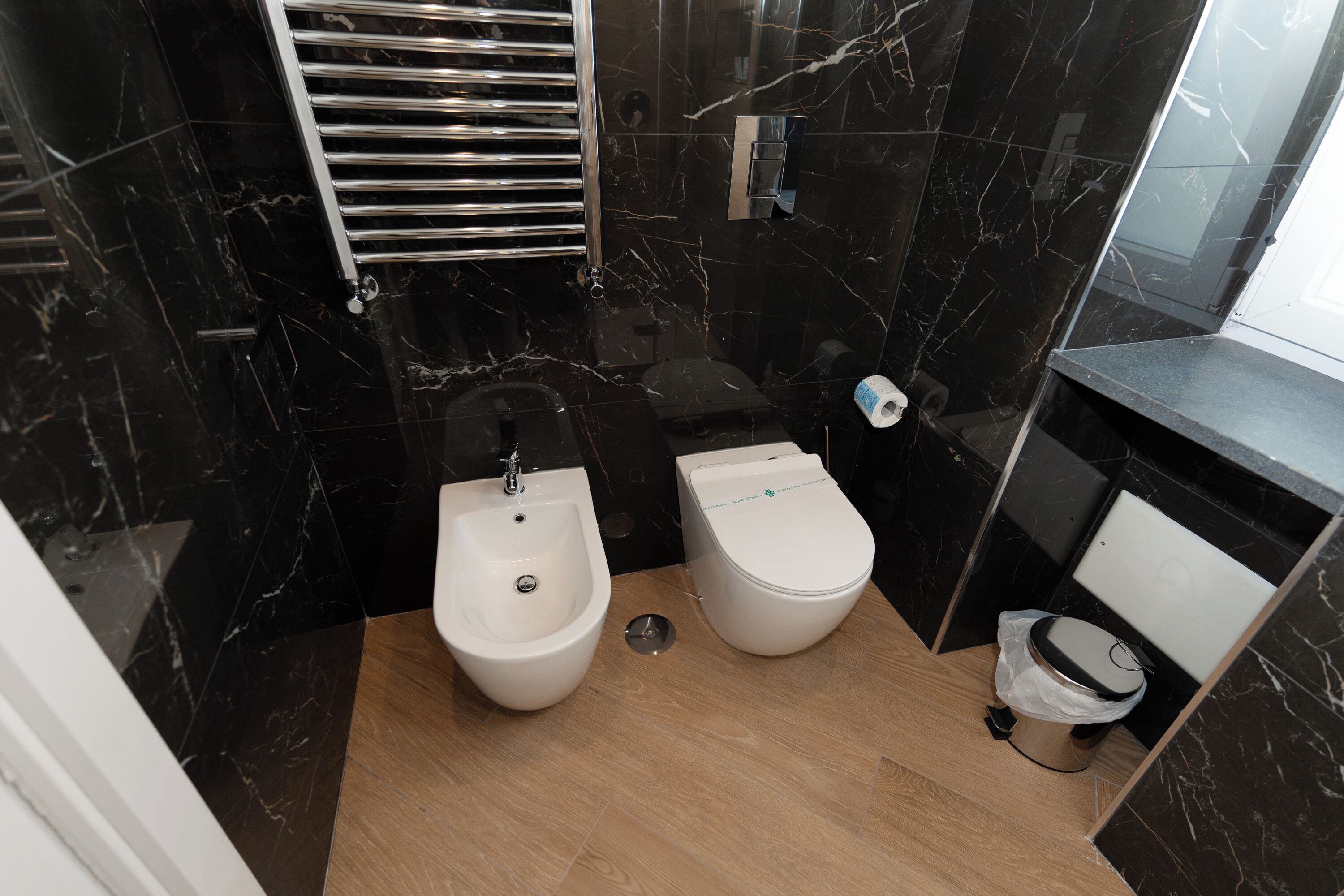 A compact bathroom with a bidet, a toilet, and a sink.