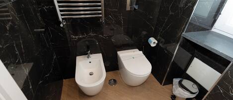 A compact bathroom with a bidet, a toilet, and a sink.