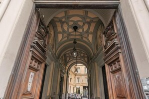 An arched corridor with ornate woodwork and a hanging light fixture. - Palazzetto Santa Lucia (Naples)
