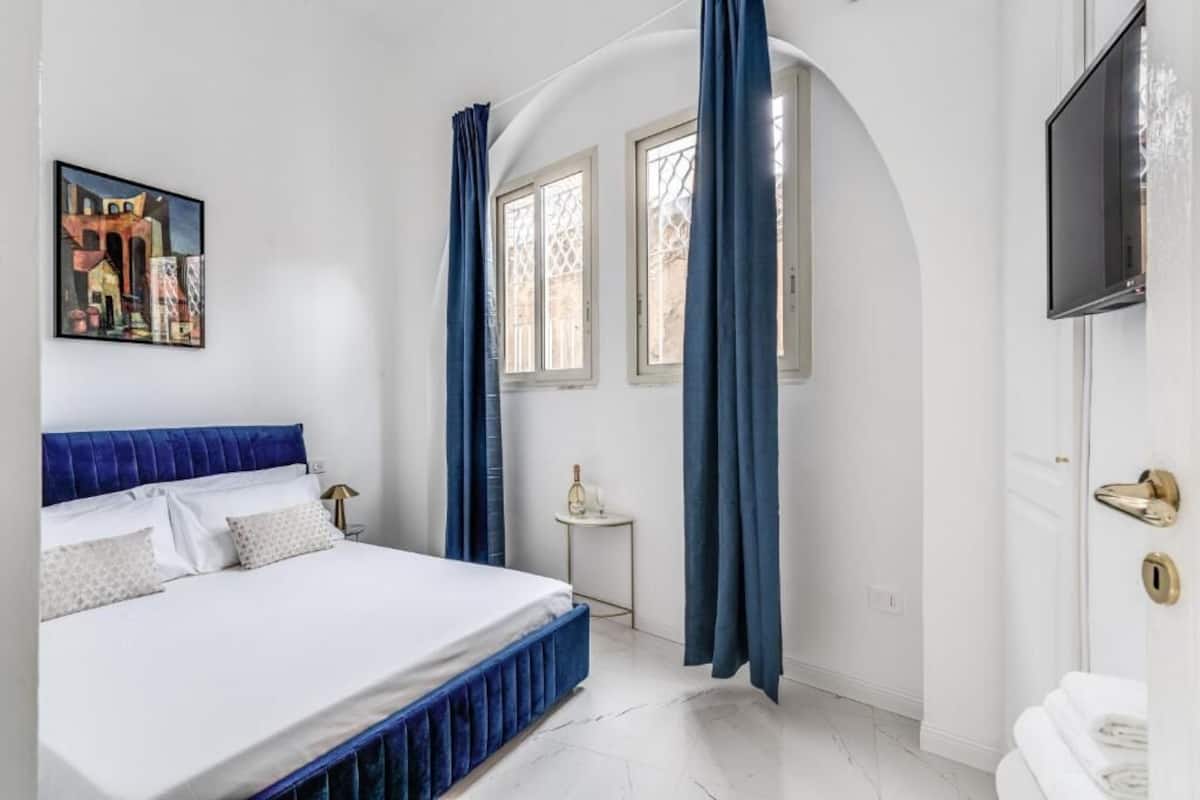 A bedroom with a bed, a TV, and a painting on the wall.