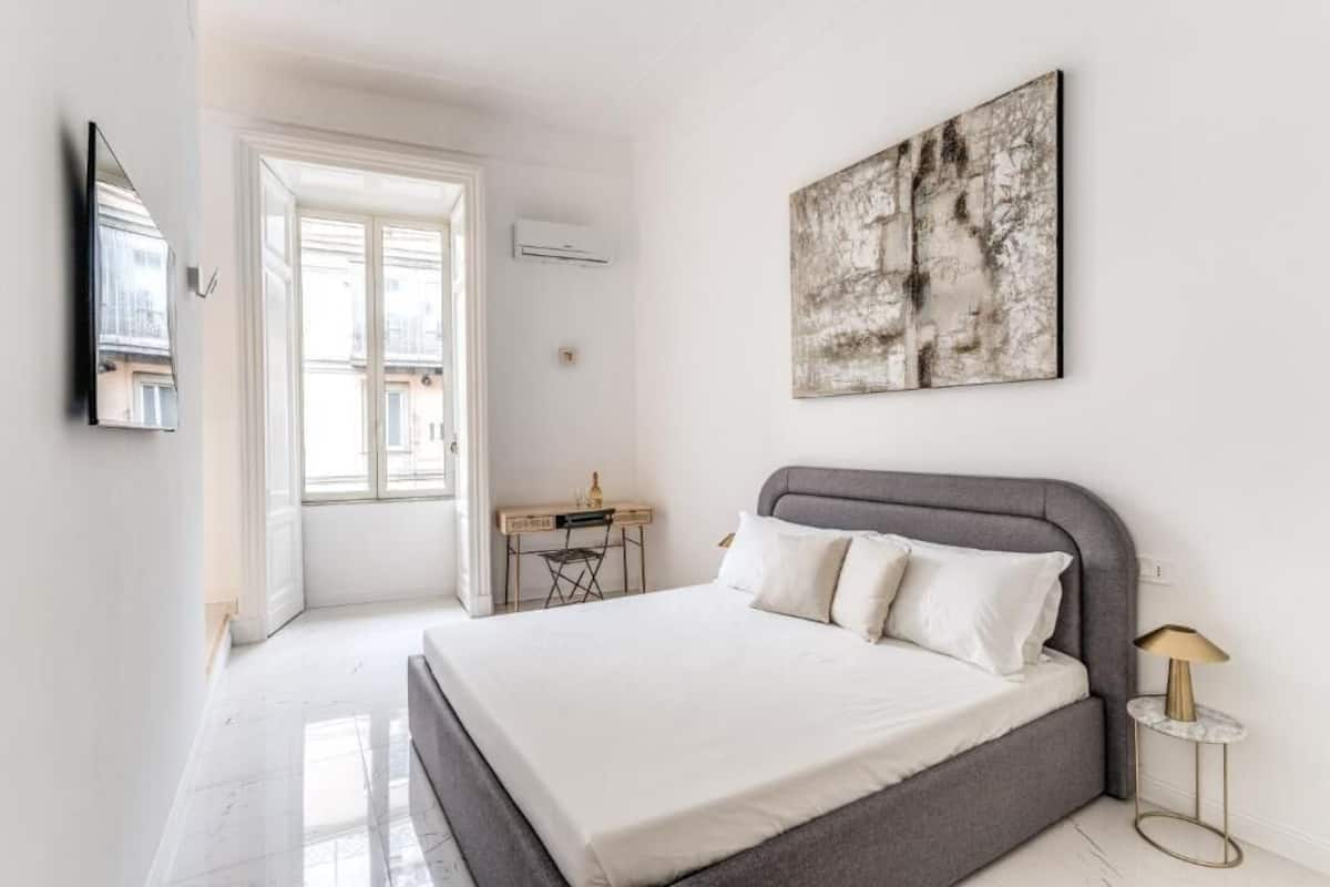 A bedroom with a bed, a desk, and a chair.