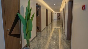 Un pasillo con puertas de madera, una planta en maceta y suelo de mármol.