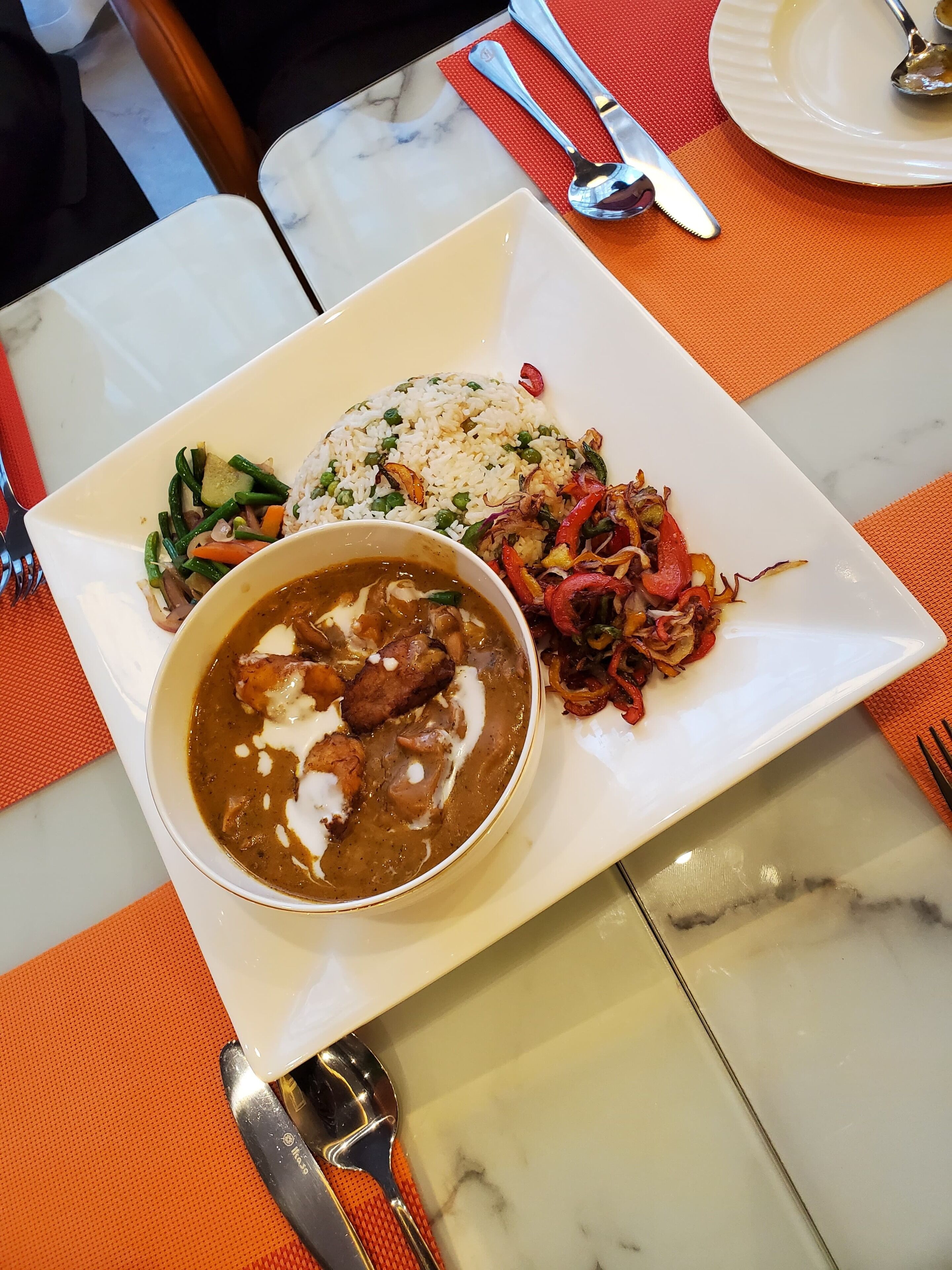 A plate of food with rice, vegetables, and a curry dish.