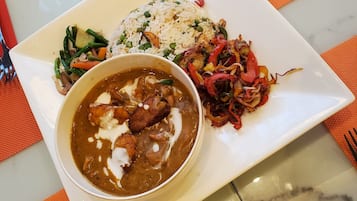 A plate of food with rice, vegetables, and a curry dish.