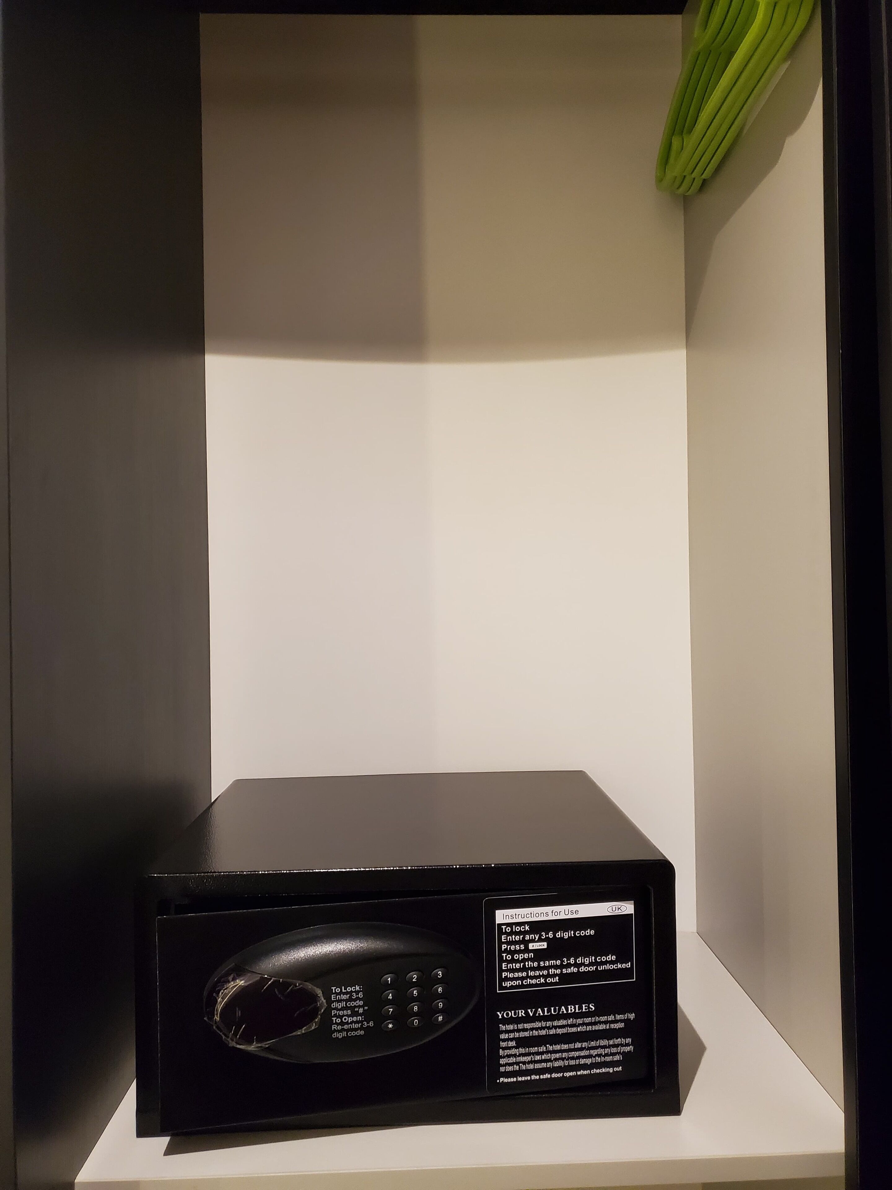 Un four à micro-ondes noir, posé sur une étagère blanche, avec les instructions d’utilisation visibles sur le côté.