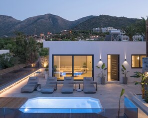 A modern outdoor pool area with lounge chairs, a hot tub, and a view of a mountain range. - Mousses Villa, with Pool & Spa Whirlpool by the Beach (CQ4M+QX3 Bali, Greece)