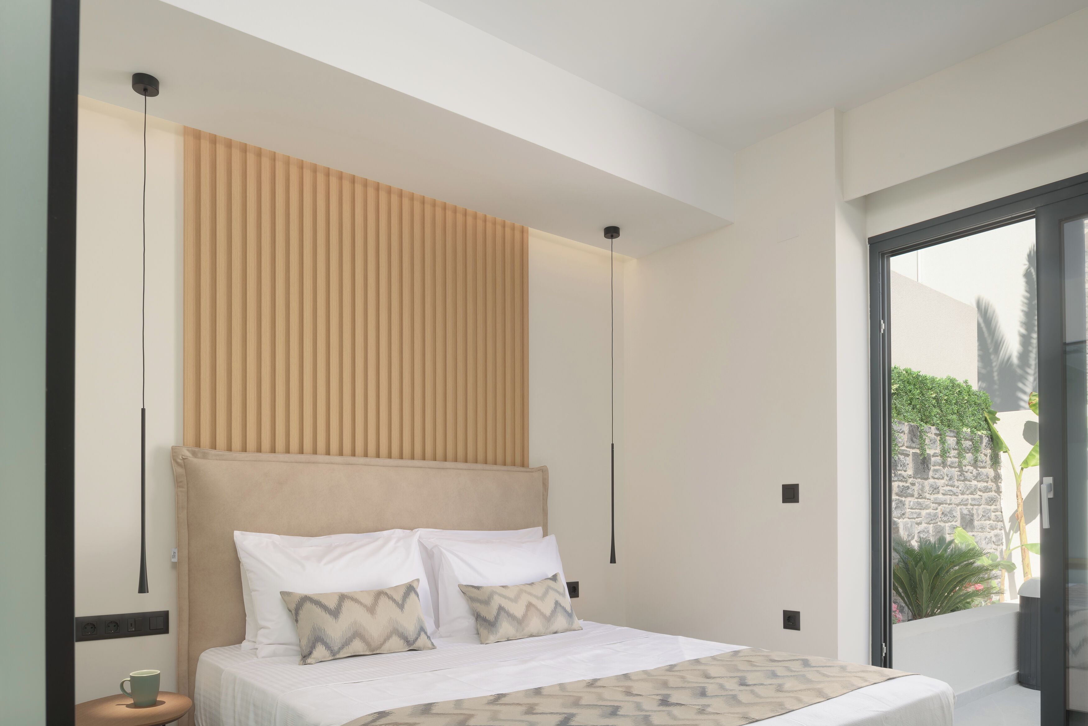 Un dormitorio moderno con una cama grande, cabecera y vistas a zonas verdes.