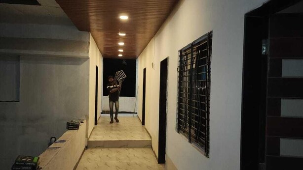 Un pasillo estrecho con techo de madera e iluminación empotrada, que conduce a una puerta con reja de metal.