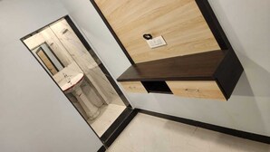 Un baño moderno con tocador de madera, lavamanos y espejo.