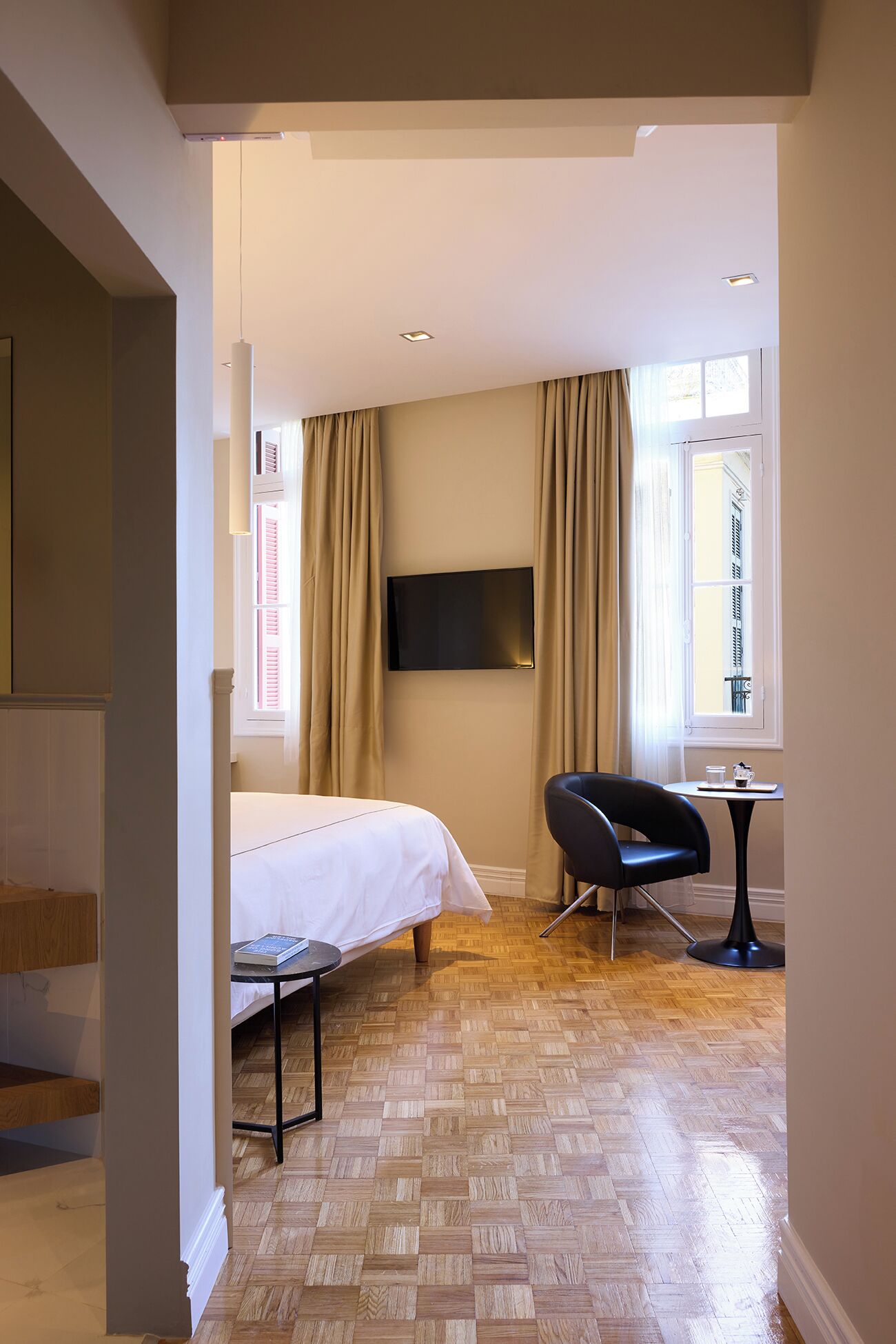 A hotel room with a bed, a desk, a chair, a television, and a window with curtains.