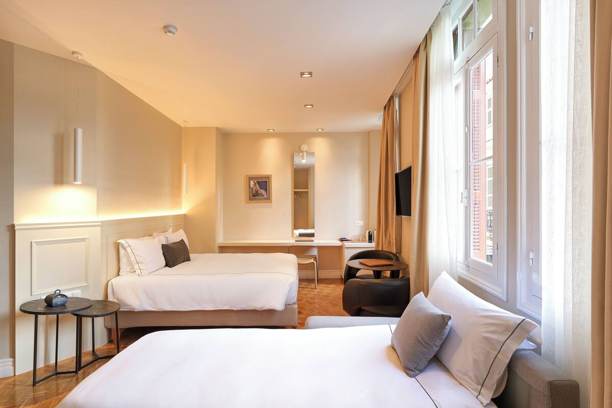 Ett hotellrum med två sängar, ett skrivbord, en stol och en tv.