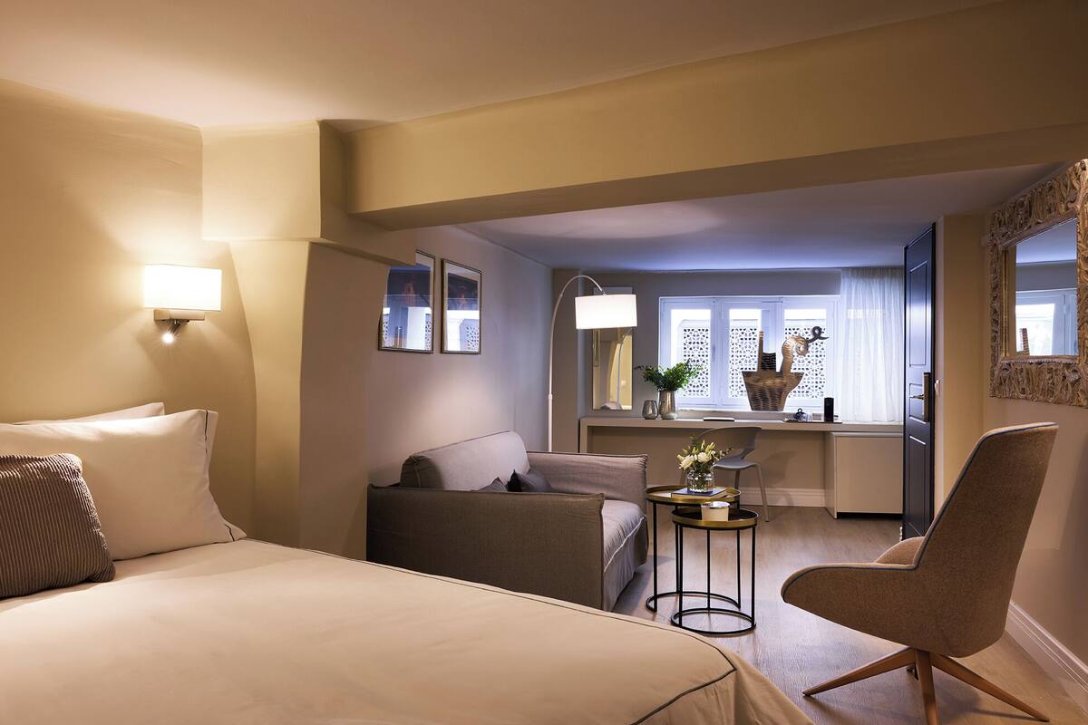 Ett hotellrum med en säng, en soffa, en stol, ett litet bord och ett fönster med utsikt.