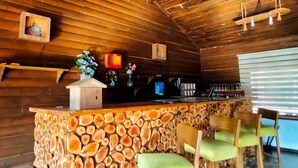 Ein rustikales Holzinterieur mit einer Steintheke, Holzstühlen und einer hängenden Leuchte.