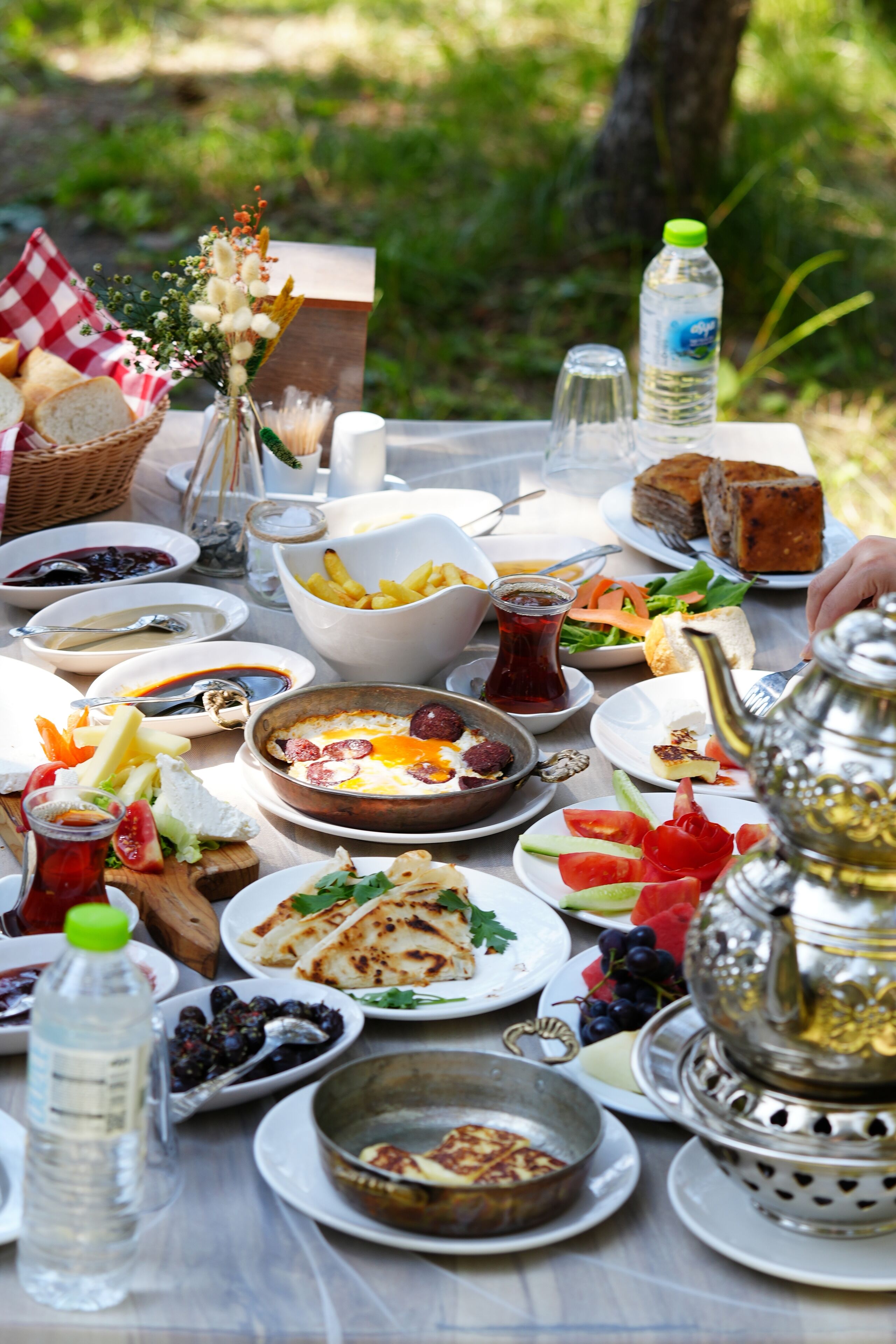 Una mesa dispuesta con varios platos, incluyendo pan, ensalada y una tetera, que sugiere un ambiente para comer.