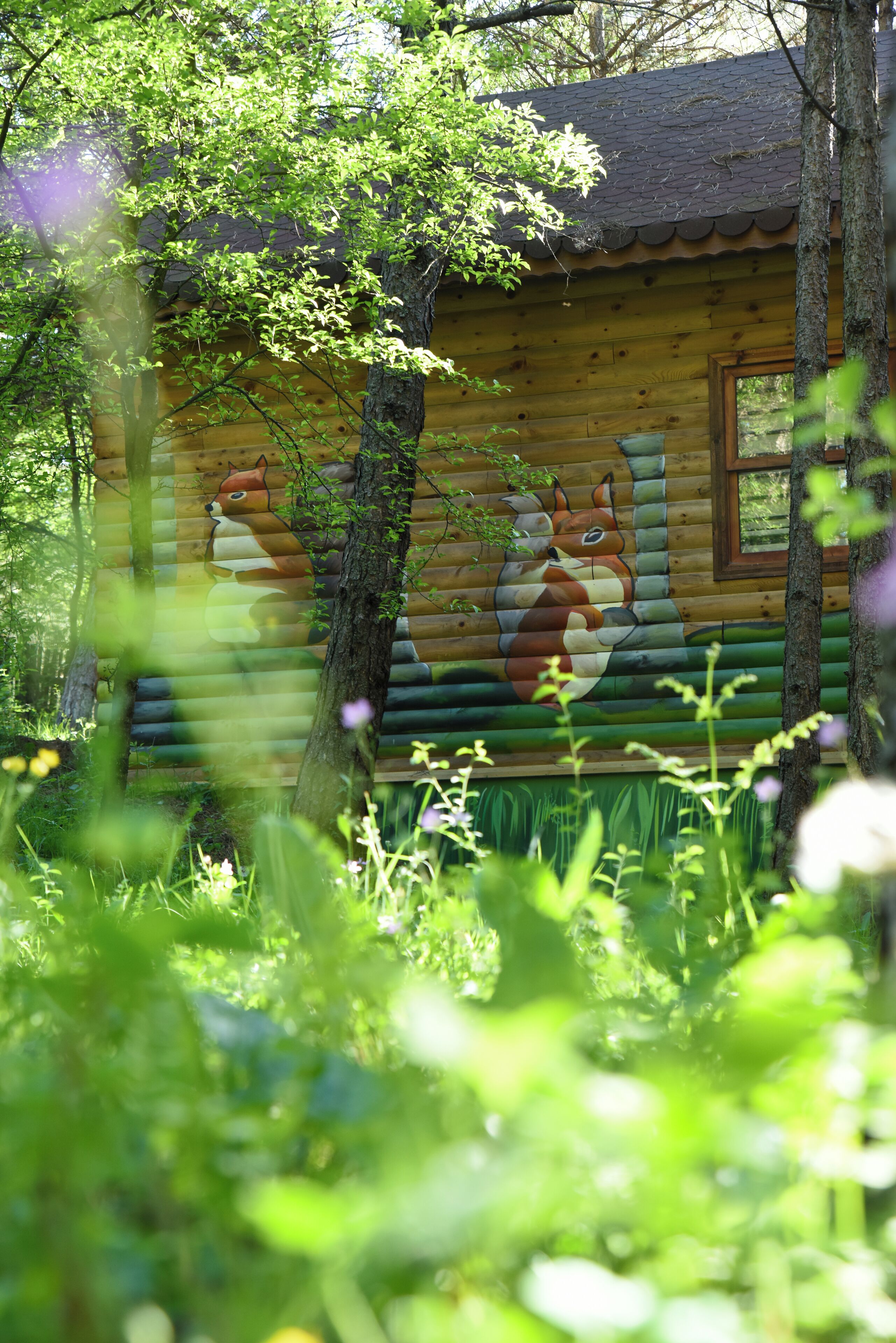 A log cabin with a mural of a fox and a squirrel.