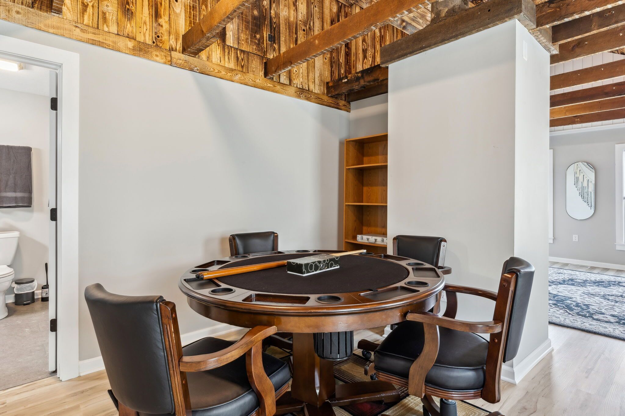 A room with a round wooden table, six chairs, and a pool table.