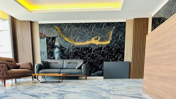 A modern living room with a marble floor, a grey sofa, and a wooden accent wall. - The Hera Gold Hotel (Istanbul)