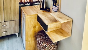 A compact room with a wooden desk, a small cabinet, a mirror, and an air conditioning unit mounted on the wall. - The Hera Gold Hotel (Istanbul)