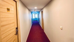 A hotel hallway with wooden doors, a red carpet, and a ceiling light. - The Hera Gold Hotel (Istanbul)