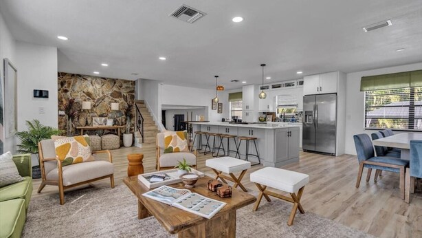 A modern living room with a wooden coffee table, a sofa, and a dining area with a table and chairs.
