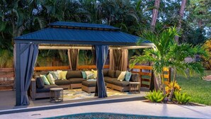 A covered outdoor seating area with a pool.