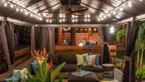 An outdoor patio with a sofa, cushions, and potted plants.