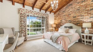 A bedroom with a large window, a bed, a desk, and a chair.