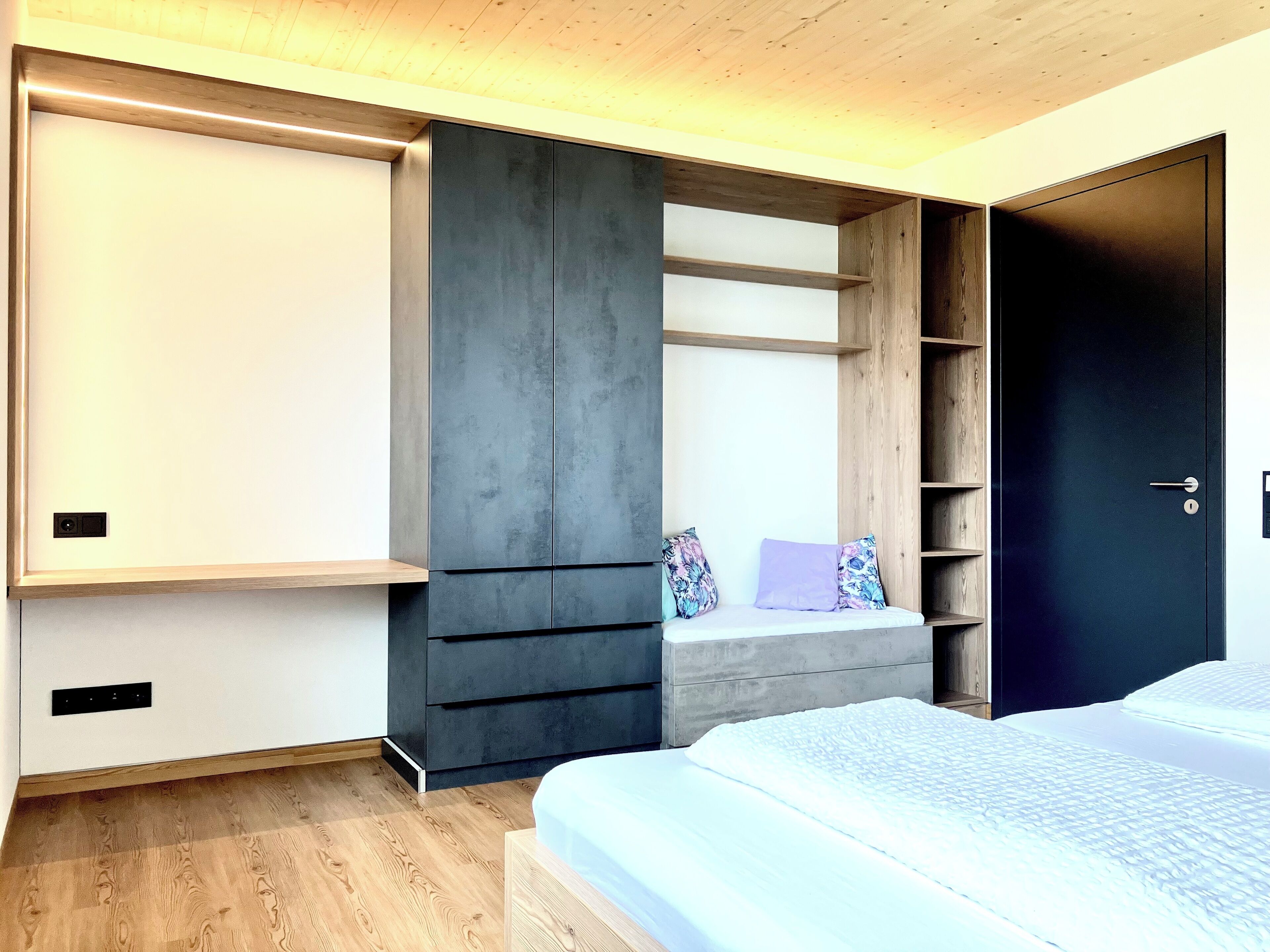 A bedroom with a bed, built-in wardrobe, and a bench with cushions.