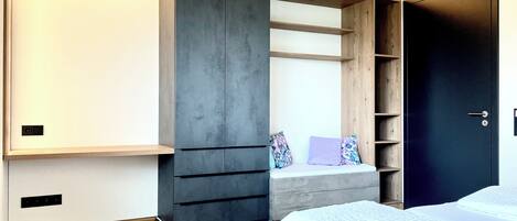 A bedroom with a bed, built-in wardrobe, and a bench with cushions.