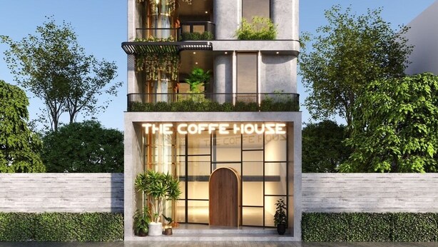 Un edificio de varios pisos con balcones, la entrada a una cafetería y vegetación.