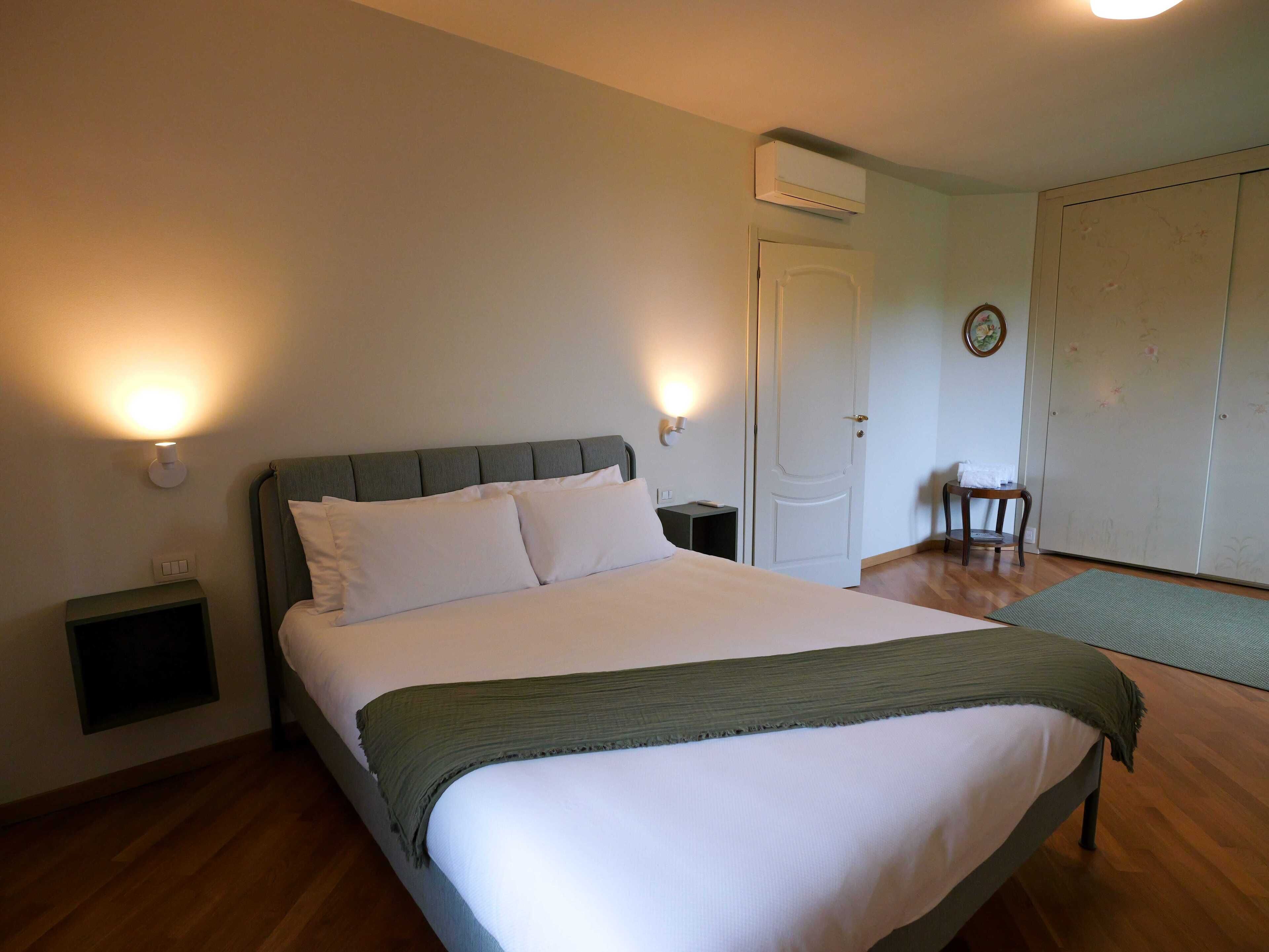 A bedroom with a bed, bedside tables, a chair, and a wardrobe.