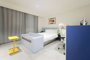 Une chambre d’hôtel moderne équipée d’un lit, d’un bureau, d’une chaise et d’une grande fenêtre avec des rideaux.
