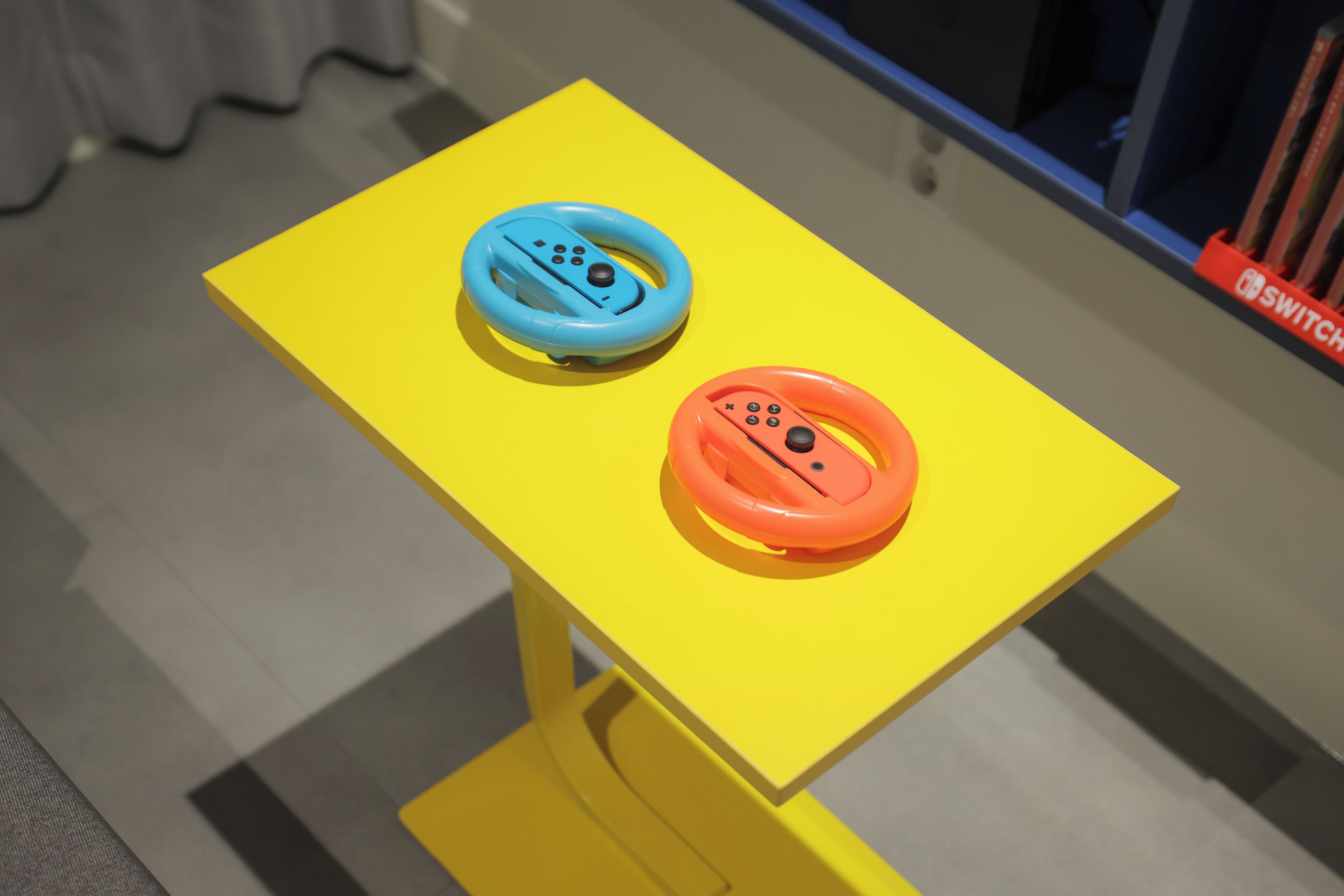 Two steering wheels on a yellow table.