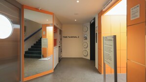 Een hotel lobby met een trap, een self-check-in zone en een klok.